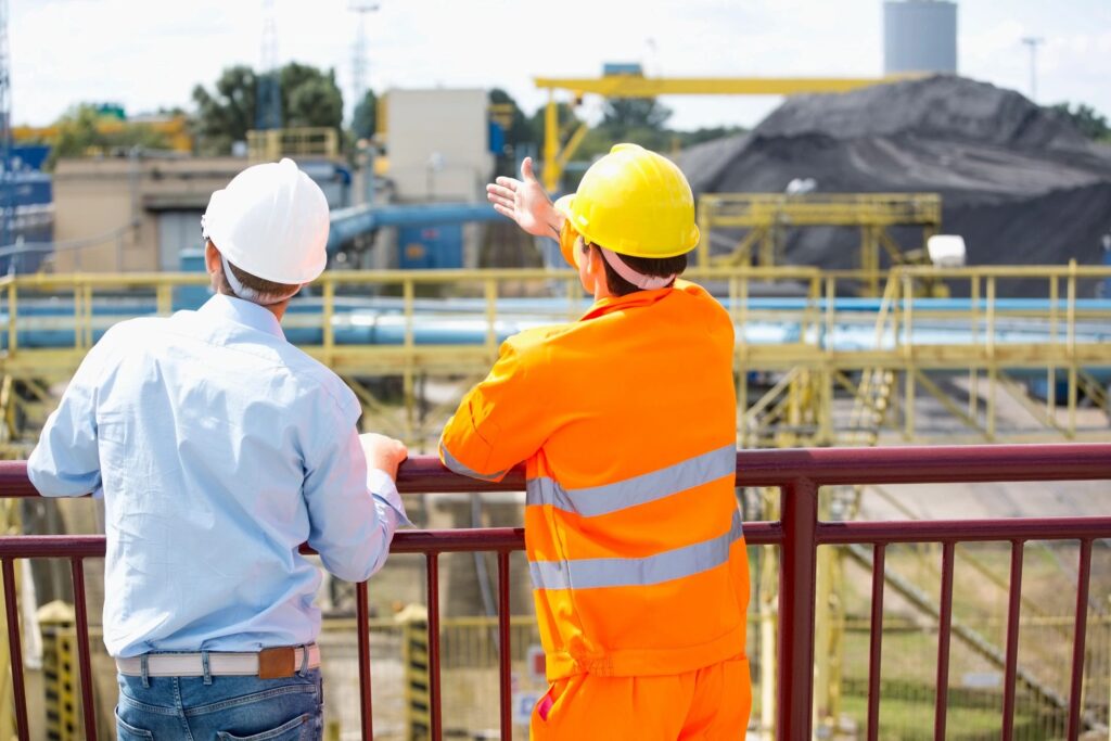 Two men in construction caps discussing with each other